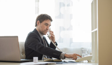 real estate agent dialing telephone number sitting at his office desk