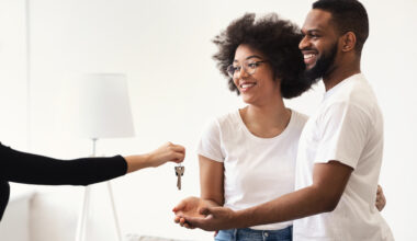 Real Estate Agent Giving House Key To Black Couple Indoors