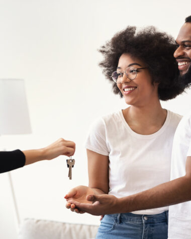 Real Estate Agent Giving House Key To Black Couple Indoors